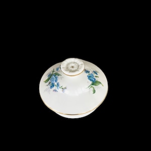 May include: White porcelain lid with a gold trim and a floral design featuring blue forget-me-not flowers.