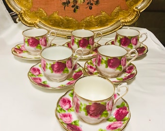 May include: A set of six teacups and saucers with a floral pattern. The cups and saucers are white with pink roses and green leaves. The cups have gold rims.