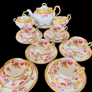 May include: A vintage tea set with a floral pattern and gold accents. The set includes a teapot, creamer, sugar bowl, and six teacups and saucers.