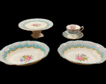 May include: A set of four vintage porcelain teacups and saucers with a blue and white floral pattern. The set includes a cake stand, a teacup and saucer, and two oval serving dishes.