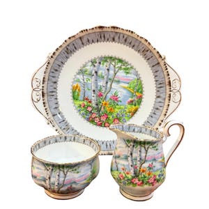 Puede incluir: Un juego de té de porcelana blanca con un diseño de abedul. El juego incluye una jarra de crema, un azucarero y un plato de servir con borde festoneado.