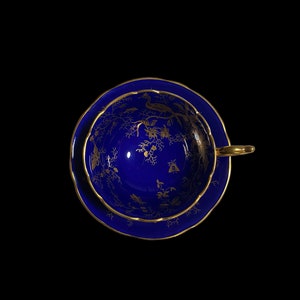 May include: A blue and gold teacup and saucer with a floral pattern. The cup and saucer are decorated with gold trim and a delicate floral design.