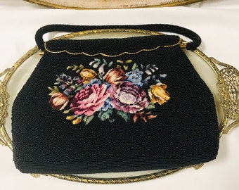 May include: A black beaded evening bag with a floral embroidered design. The bag has a gold-tone clasp and a chain strap.