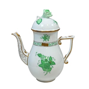 Puede incluir: Tetera de porcelana blanca con diseños florales verdes y ribetes dorados. La tapa presenta un asa en forma de rosa verde. La boquilla y el asa también están acentuadas con dorado. Una pieza decorativa para servir té o café.