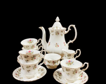 Op de afbeelding: Een wit theeservies met een bloemenpatroon. De set bevat een theepot, roomkan, suikerpot en vier theekopjes met schoteltjes.