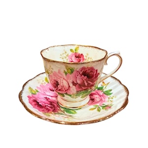 May include: A white teacup and saucer with a pink rose floral pattern and gold trim. The cup and saucer are made of fine china.
