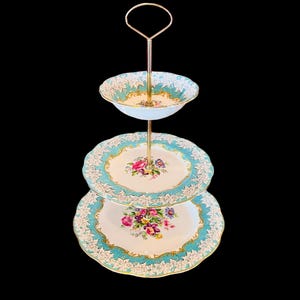 May include: A three-tier cake stand with a gold metal stand and blue and white floral patterned porcelain plates.