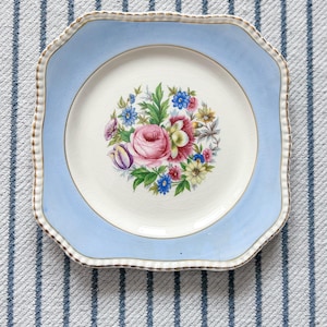 May include: A white ceramic mug with a black handle and the text "But First, Coffee" in a handwritten style. The mug is on a white surface. The mug is approximately 4 inches tall.