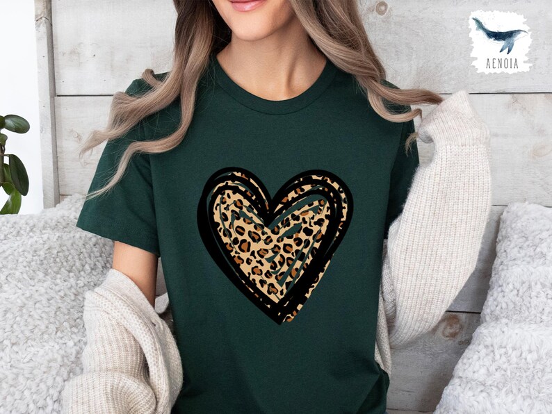 Puede incluir: Una camiseta verde oscuro con un gran gr&aacute;fico de coraz&oacute;n con contorno negro. El coraz&oacute;n est&aacute; relleno con un patr&oacute;n de estampado de leopardo.
