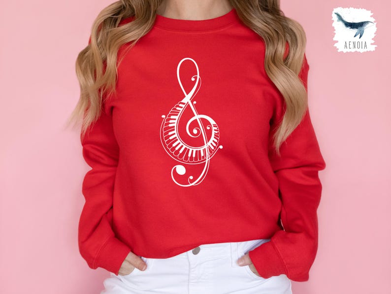 Peut inclure: Un sweat-shirt rouge avec un motif de cl&eacute; de sol blanche orn&eacute; d'un clavier de piano. Le motif est complexe et d&eacute;taill&eacute;.