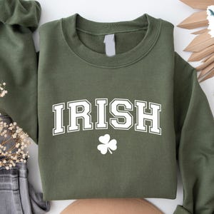 May include: A green sweatshirt with the word "IRISH" in white letters with a white shamrock underneath.
