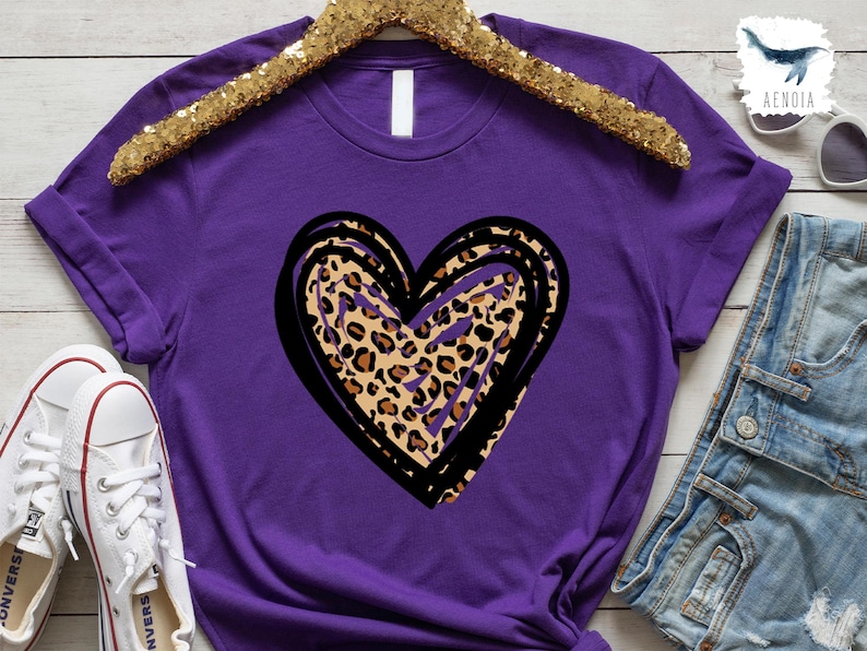 Puede incluir: Camiseta morada con un contorno negro y blanco de un coraz&oacute;n relleno de un estampado de leopardo.