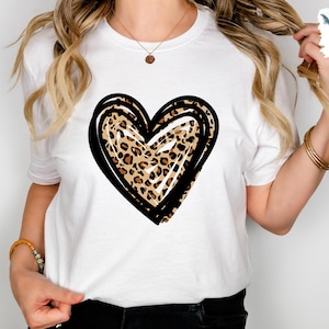 Puede incluir: Camiseta blanca con un contorno negro y blanco de un coraz&oacute;n relleno de un estampado de leopardo.