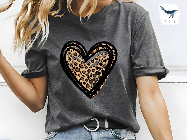 Puede incluir: Una camiseta gris con un dise&ntilde;o de coraz&oacute;n de estampado de leopardo negro y marr&oacute;n.