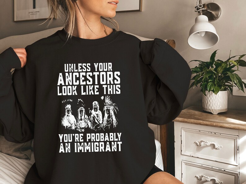 May include: Black sweatshirt with white text that reads "Unless your ancestors look like this you're probably an immigrant". The text is surrounded by an illustration of four Native American people.