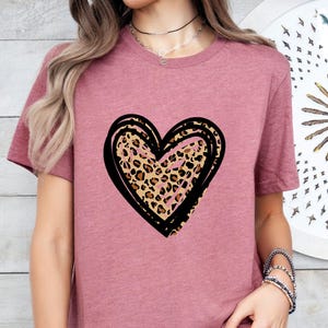 Puede incluir: Una camiseta color malva con un coraz&oacute;n de contorno negro con un estampado de leopardo.