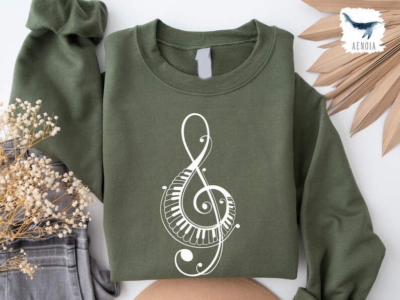 Peut inclure: Un sweat-shirt vert avec un motif de cl&eacute; de sol blanche. La cl&eacute; de sol est compos&eacute;e de touches de piano.