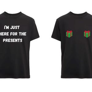 May include: Two black t-shirts. One has the text "I'M JUST HERE FOR THE PRESENTS" in white. The other has two gift box graphics with red bows and green wrapping. Both shirts have short sleeves.