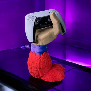 May include: A red and blue hand-shaped stand holds a white and black video game controller. The stand is designed to look like a character from a popular video game.