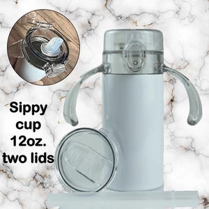 Puede incluir: Vaso con boquilla blanco con dos tapas transparentes y asas. El vaso tiene una capacidad de 355 ml. Tambi&eacute;n se muestra el texto "Sippy cup 12oz. two lids."
