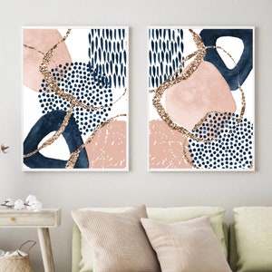 May include: Two framed abstract art prints. Each print features a white background with navy blue, blush pink, and gold glitter accents. The designs include organic shapes and dotted patterns, creating a modern aesthetic.