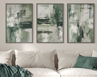 May include: Three framed abstract art prints with a green and white color scheme. The prints are hung on a white wall above a white couch with green throw pillows and a green blanket.
