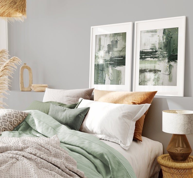 May include: A bedroom with a green and white bedding set, two framed abstract paintings with green and white brushstrokes, a wooden nightstand with a lamp, and a woven basket.