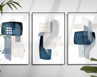 May include: Set of three abstract art prints featuring blue, grey, and beige watercolour shapes. The prints are framed in black frames.
