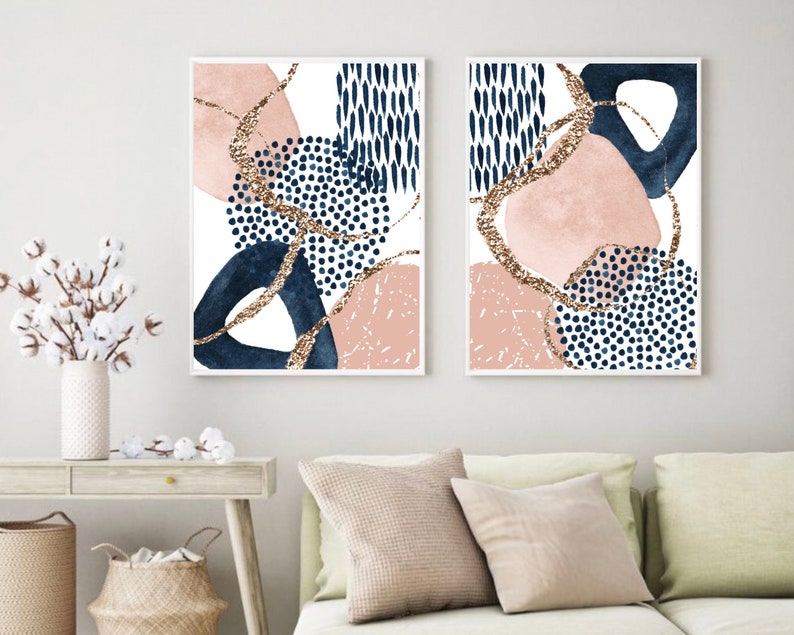 May include: Two framed abstract art prints. Each print features a white background with navy blue, blush pink, and gold glitter accents. The designs include organic shapes and dotted patterns, creating a modern aesthetic.