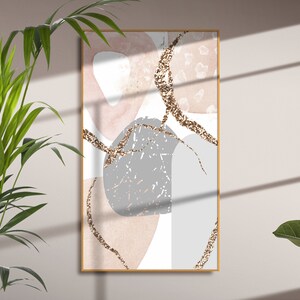 K&ouml;nnte beinhalten: Abstrakter Kunstdruck mit rosa, grauen und wei&szlig;en Formen mit goldenen Glitzerakzenten. Der Druck ist in einem d&uuml;nnen Holzrahmen gerahmt.