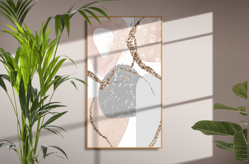 K&ouml;nnte beinhalten: Abstrakter Kunstdruck mit rosa, grauen und wei&szlig;en Formen mit goldenen Glitzerakzenten. Der Druck ist in einem d&uuml;nnen Holzrahmen gerahmt.