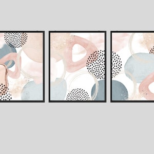 K&ouml;nnte beinhalten: Drei abstrakte Kunstdrucke mit wei&szlig;em Hintergrund und einem Mix aus rosa, blauen und beigen Formen und schwarzen Punkten.