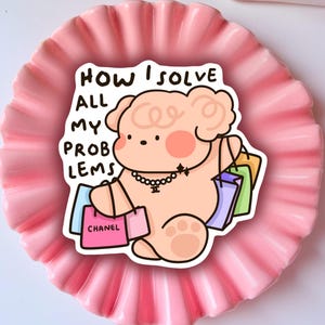 Pode incluir: Uma ilustração de desenho animado rosa e branca de um urso segurando sacolas de compras. O texto "HOW I SOLVE ALL MY PROBLEMS" está escrito acima do urso. As sacolas de compras têm as palavras "CHANEL" e outro texto.