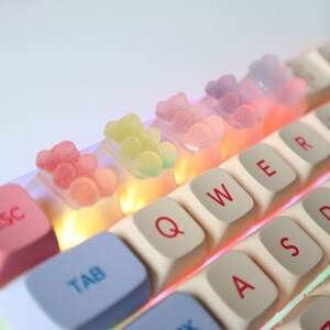 Pode incluir: Um teclado branco com doces de goma coloridos nas teclas. As teclas s&atilde;o etiquetadas com letras, n&uacute;meros e s&iacute;mbolos. O teclado tem uma tecla escape rosa e uma tecla tab azul.