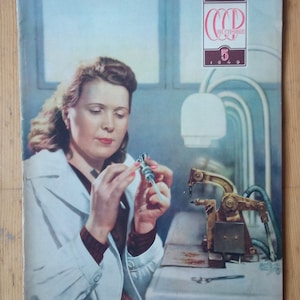 Puede incluir: Portada de revista vintage que muestra a una mujer con bata de laboratorio trabajando con equipos científicos. La portada incluye texto en ruso y la fecha de 1949. La imagen tiene una estética retro.