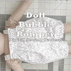 Puede incluir: Una muñeca con cabeza, brazos y piernas beiges, vestida con un pelele abombachado con estampado floral. El texto "Doll Bubble Romper Digital Sewing Pattern" está superpuesto. La muñeca está sobre una esterilla de corte gris.