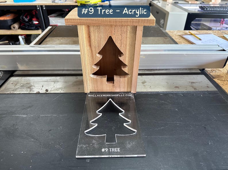 May include: A wooden box with a cutout of a Christmas tree. The box is sitting on a table next to a clear acrylic sheet with a tree cutout and the text "#9 TREE".