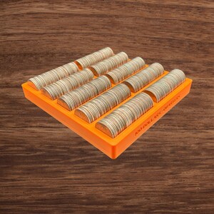 May include: An orange coin organizer filled with rolls of quarters. The text "100 DOLLARS - QUARTERS" is printed on the side. The organizer is on a wooden surface.