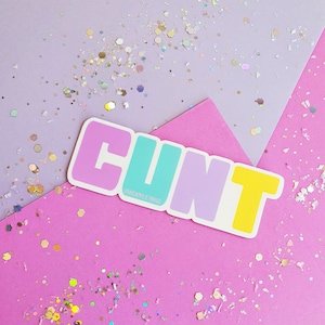 May include: A sticker with the word "CUNT" in rainbow colors on a pink and purple background with glitter. The sticker has the text "remarkable. nice" at the bottom.