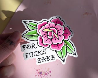 May include: A die-cut sticker featuring a pink rose with green leaves and yellow accents. The text "SNIPS TATTOOS" is printed on a leaf, and the words "FOR FUCKS SAKE" are written in black, bold, stylized lettering below the flower.