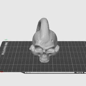 May include: A 3D printed gray skull with a horn on top. The skull is sitting on a black grid surface.