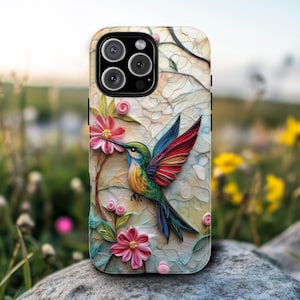 May include: A colorful phone case with a hummingbird and flowers. The hummingbird is green, red, and blue with a long beak. The flowers are pink, white, and yellow. The phone case is designed for an iPhone.