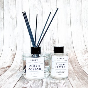 May include: Two glass bottles with black lids and black sticks. The bottles are filled with a clear liquid and have labels that read "BENEW LUXURY SCENTED CLEAN COTTON ALL NATURAL DIFFUSER 150ML" and "BENEW LUXURY SCENTED CLEAN COTTON ALL NATURAL DIFFUSER 70ML".