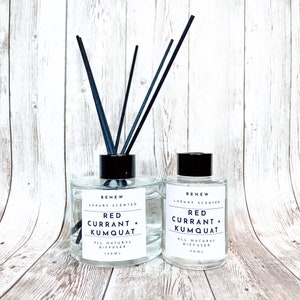 May include: Two clear glass bottles with black lids and black diffuser sticks. The bottles contain a red currant and kumquat scented diffuser. The bottles are labeled "BENEW LUXURY SCENTED RED CURRANT + KUMQUAT ALL NATURAL DIFFUSER 150ML" and "BENEW LUXURY SCENTED RED CURRANT + KUMQUAT ALL NATURAL DIFFUSER 70ML".