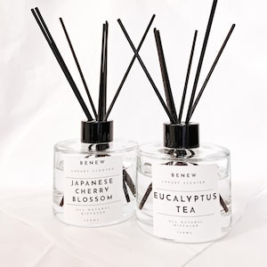 May include: Two clear glass bottles with black lids and black diffuser sticks. The bottles contain a natural diffuser. The left bottle is labeled "Japanese Cherry Blossom" and the right bottle is labeled "Eucalyptus Tea".