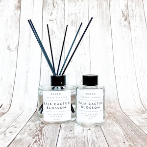 May include: Two clear glass bottles with black lids and black diffuser sticks. The bottles are labeled "BENEW LUXURY SCENTED BAJA CACTUS BLOSSOM ALL NATURAL DIFFUSER 150ML" and "BENEW LUXURY SCENTED BAJA CACTUS BLOSSOM ALL NATURAL DIFFUSER 100ML".