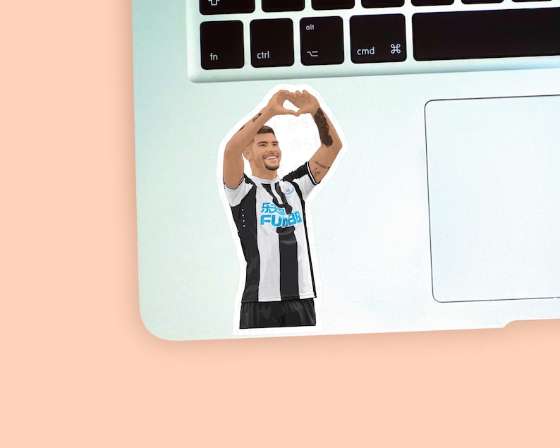 Left corner of a MacBook placed on a peach background with the Bruno Guimaraes sticker design placed on it for size reference.