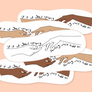 Puede incluir: Un conjunto de pegatinas ovaladas con ilustraciones de manos que se tocan. Las pegatinas presentan el texto "If it all goes wrong" y "Darling just hold on" en un estilo manuscrito, sobre un fondo melocotón.