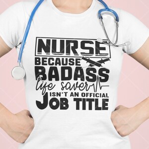 以下が含まれることがあります： 黒い文字で「ナースは、バッドアスな命の救い主だから、公式の仕事タイトルじゃないんだ」と書かれた白いTシャツ。テキストは黒い長方形で囲まれています。「バッドアス」という言葉の上に、交差した注射器が2本あります。