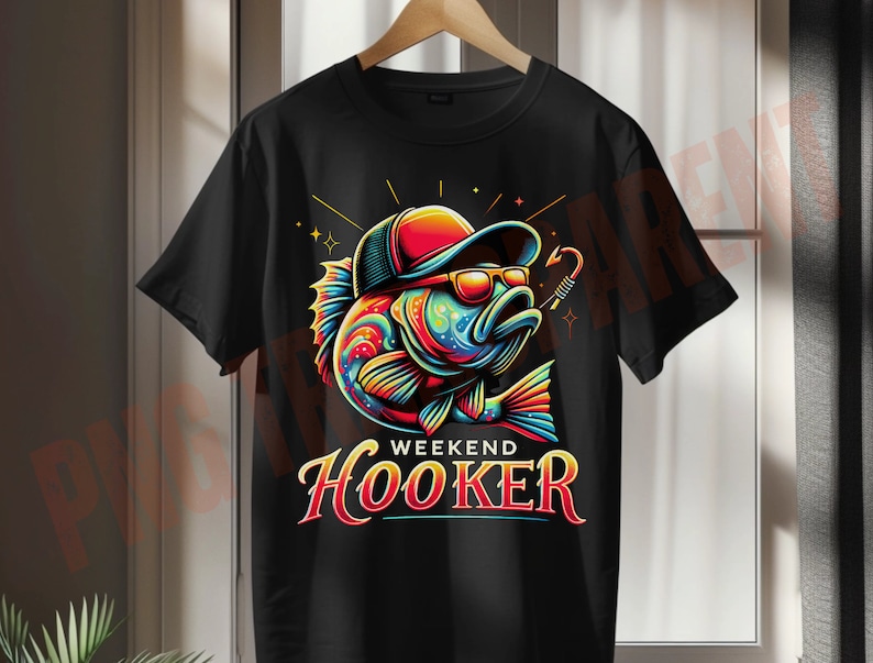 May include: Black t-shirt featuring a colorful cartoon fish wearing sunglasses and a cap. The fish has a fishing hook and the text "WEEKEND HOOKER" in a stylized font. The design includes bright colors and star accents.